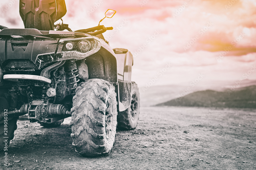 Quadricycle or quad bike on the mountains background on a cloudy day