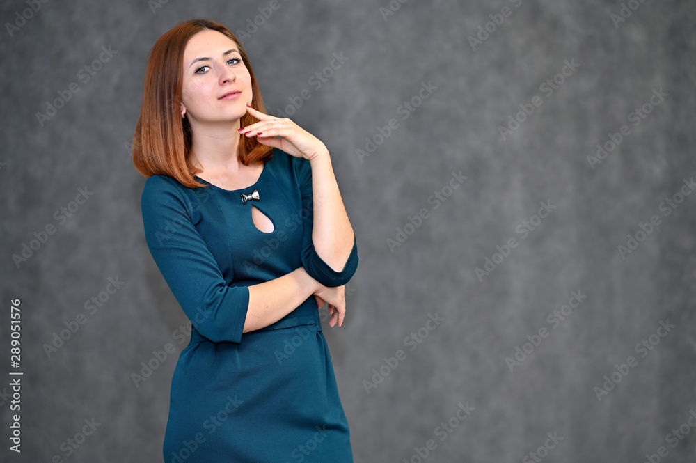 Portrait of a brunette girl with beautiful brown hair in a dark green dress on a white background. Standing in different poses, showing emotions. Portrait of a brunette girl with beautiful brown hair in a dark green dress on a white background. Standing in different poses, showing emotions.