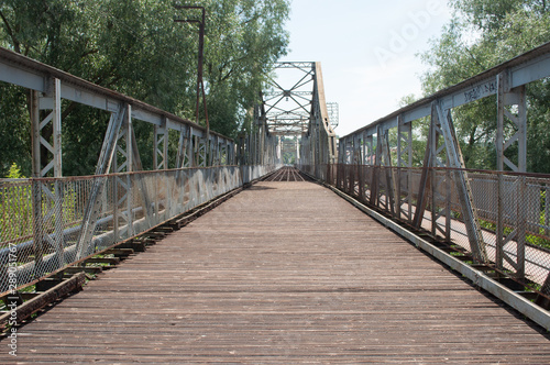 Road through the steel bridge near the trees