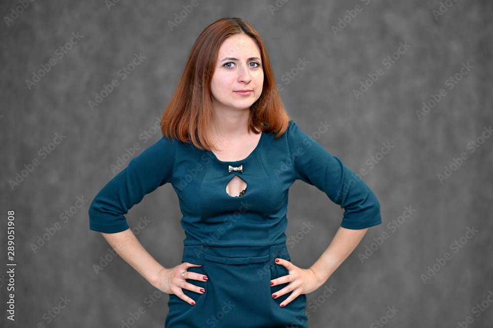 Portrait of a brunette girl with beautiful brown hair in a dark green dress on a white background. Standing in different poses, showing emotions. Portrait of a brunette girl with beautiful brown hair in a dark green dress on a white background. Standing in different poses, showing emotions.