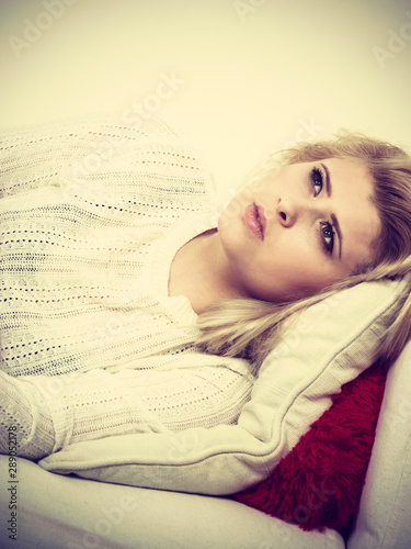 Woman lying on couch feeling very unwell photo