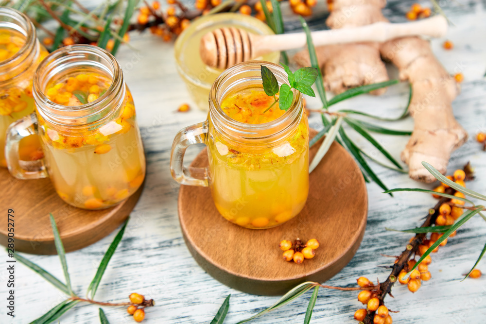 Hot sea buckthorn tea with ginger and honey and sea buckthorn berries on white table. Top view. Vitaminic healthy. Hot sea buckthorn tea with ginger and honey and sea buckthorn berries on white table. Top view. Vitaminic healthy.