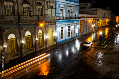Night on a Cuban street after the rain with lights and moving cars