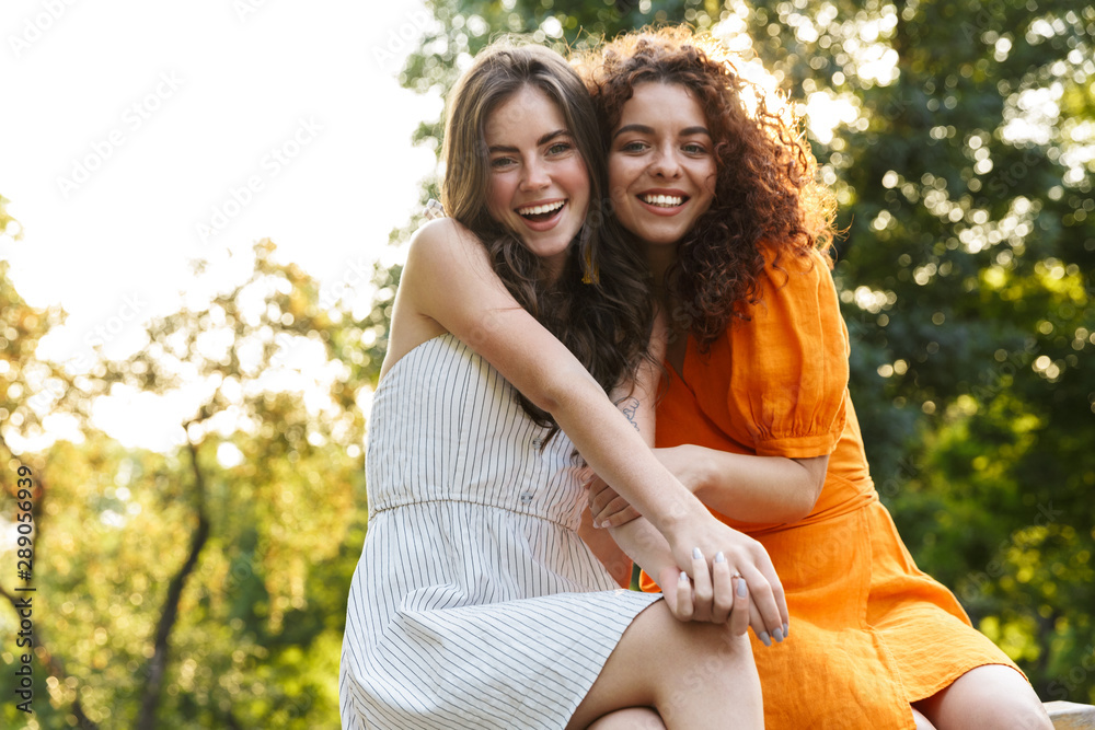 Two cheerful young girls friends spending time outdoors Two cheerful young girls friends spending time outdoors