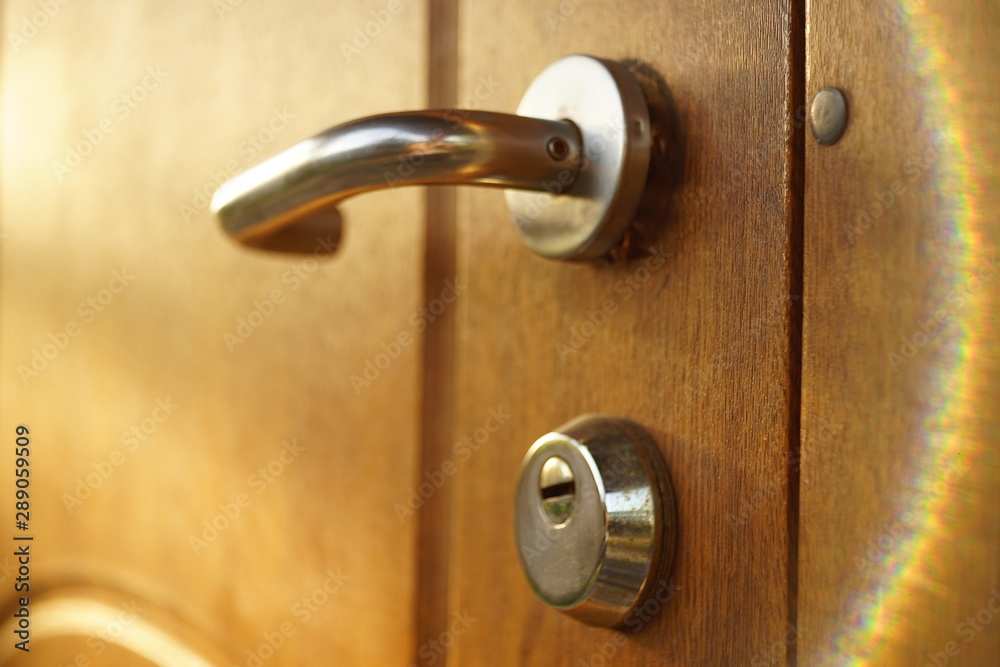 brown wooden door with chrome handle and keyhole, beautiful sunrays brown wooden door with chrome handle and keyhole, beautiful sunrays