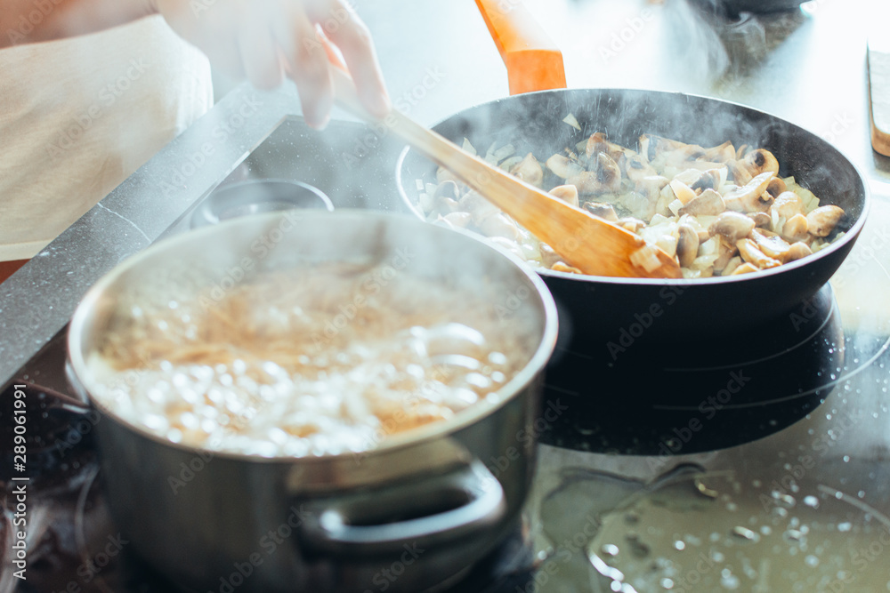 smoking pans on the kitchen. A hand stirring some mushrooms