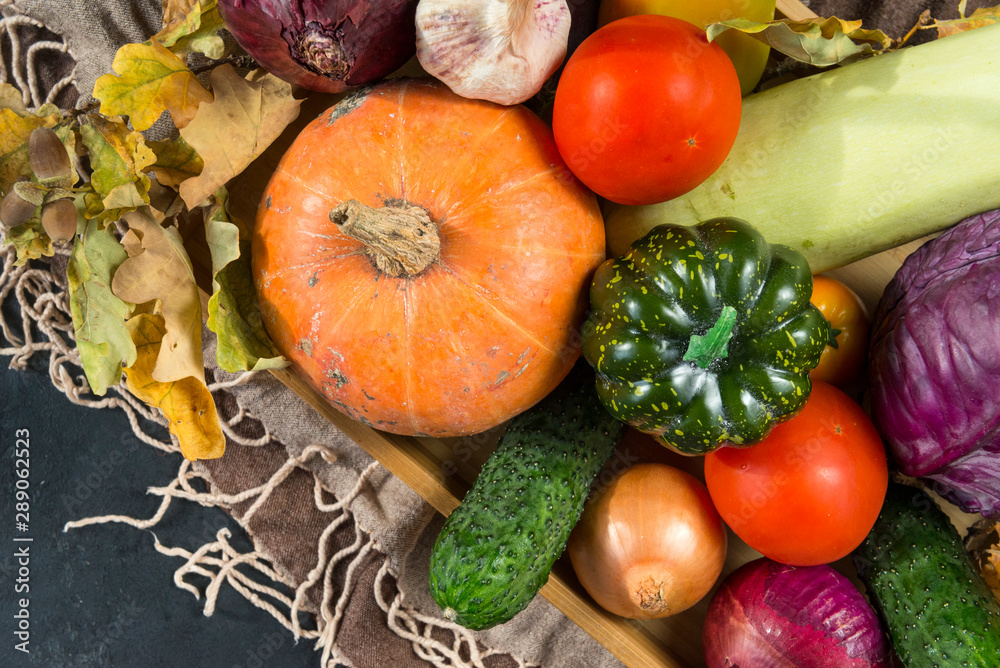 lots of autumn fresh vegetables, pumpkins, tomatoes, cabbage, zucchini, onions, dry fallen leaves, cucumber, garlic, top view