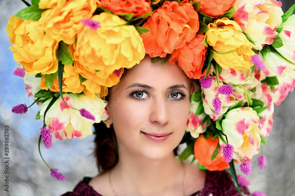 A large portrait of a pretty girl with a floral wreath on her head on a colorful background. Smiles, happiness, beauty. A large portrait of a pretty girl with a floral wreath on her head on a colorful background. Smiles, happiness, beauty.