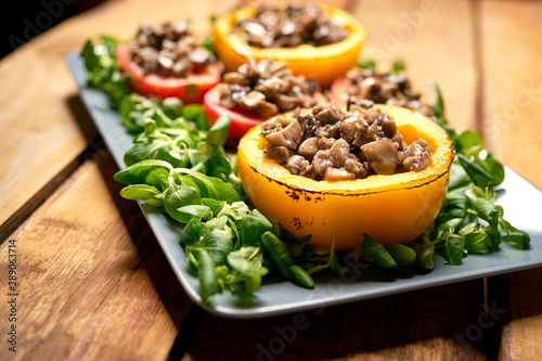 Peppers stuffed with champignons with lettuce on wooden table
