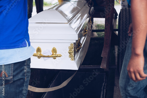 Pallbearers carefully oversee the process of lowering the casket to the ground for the deceased to its final place of rest, during the burial service or ceremony or funeral rite in the cemetery.  photo