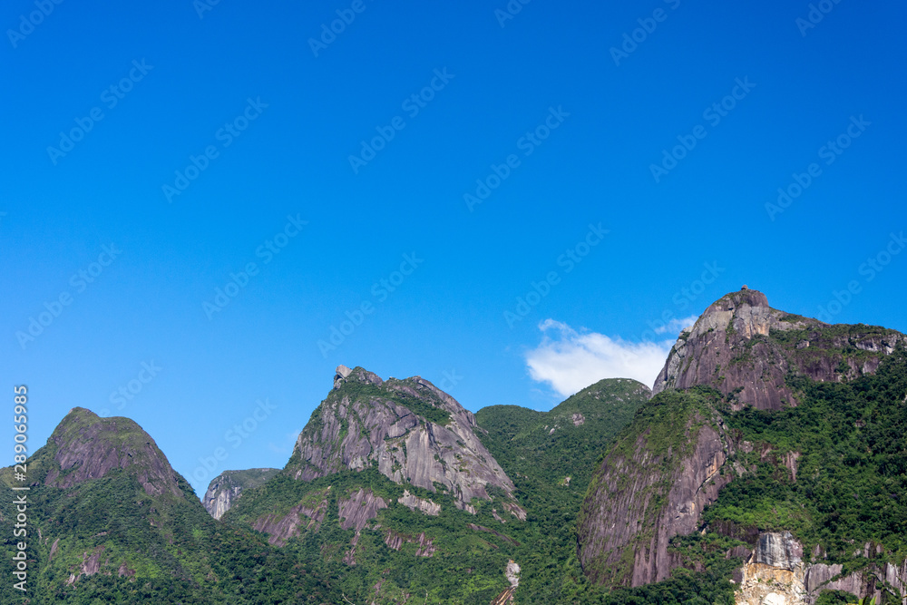 Naklejka premium Postcard trail view where you can observe in detail de vegetation and topography of the to Serra dos Orgãos (Organs Mountain) with Finger's God highlighted in landscape.