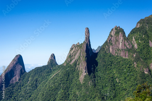Postcard trail view where you can observe in detail de vegetation and topography of the to Serra dos Orgãos (Organs Mountain) with Finger's God highlighted in landscape.