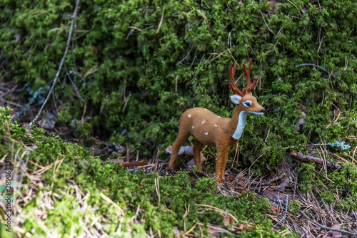 Fototapeta Naklejka Na Ścianę i Meble -  Little Toy Deer in a Green Forest on a Sunny Day