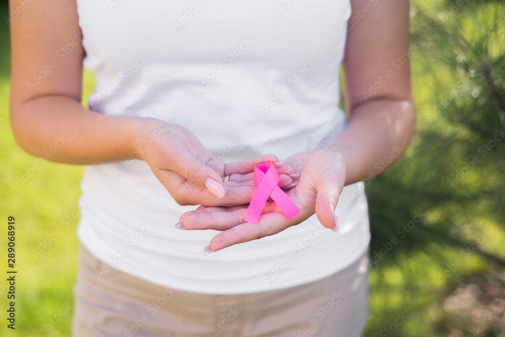 The girl holding a pink ribbon, symbol of cancer. Breast cancer awareness month.Strong woman fights cancer. The girl holding a pink ribbon, symbol of cancer. Breast cancer awareness month.Strong woman fights cancer.