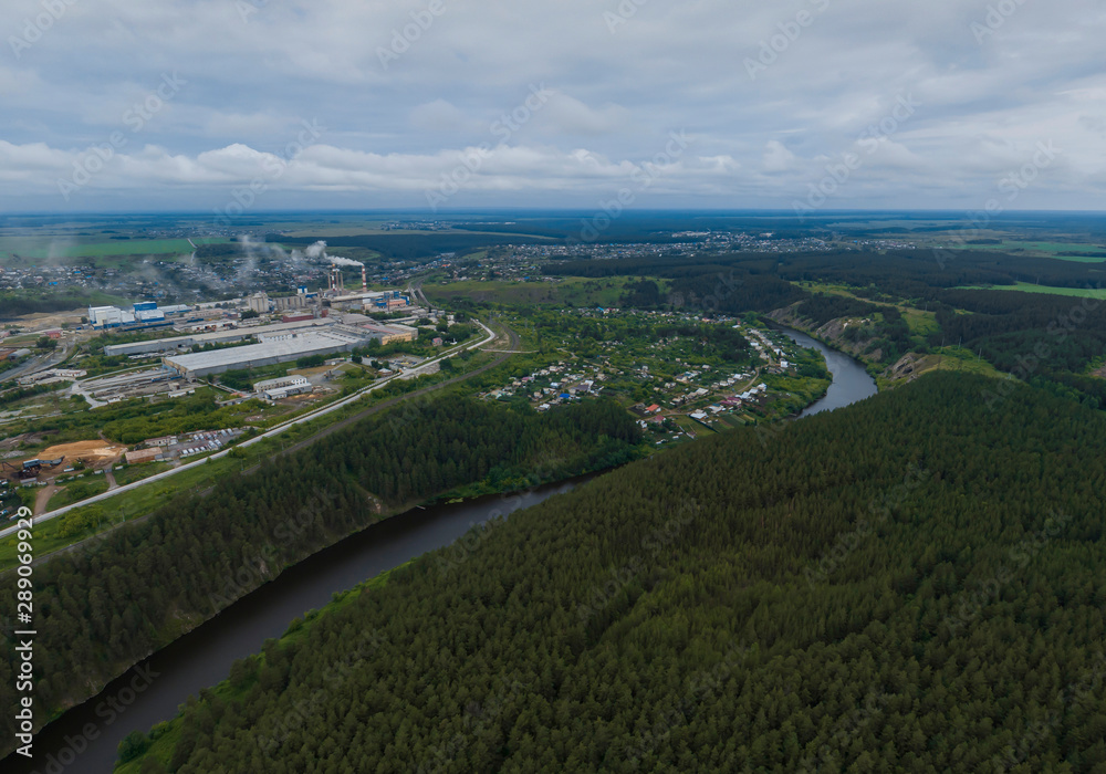 Sukhoy Log city, Pyshma river, dark forest and cement factory. Russia, Aerial, cloudu day