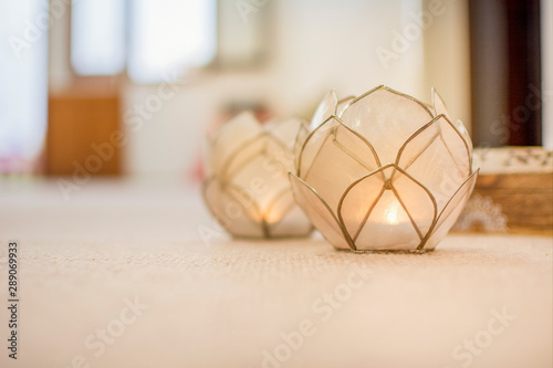 Two candlesticks shaped like a lotus flower, made of glass, with candles burning, inside the yoga gym. Copyspace on the left side. photo