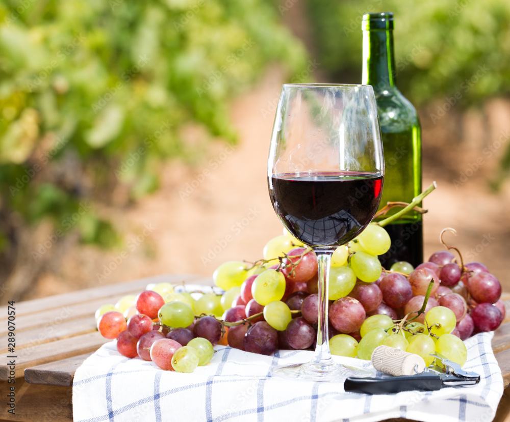 glass of red wine and ripe grapes on table