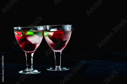 cocktail with ice mint strawberries cherries kiwi in glasses on a black background one