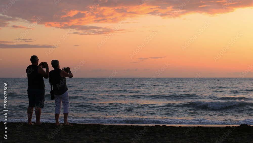 Italia, regione Toscana. Persone sulla spiaggia al tramonto