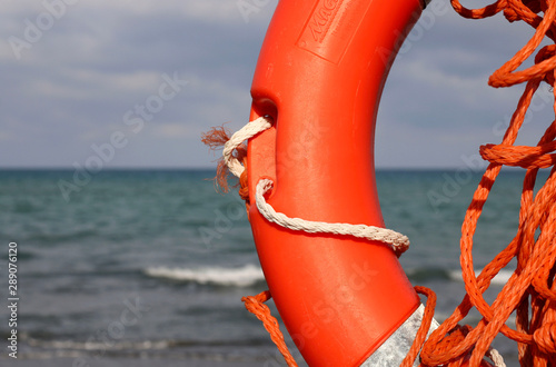 Salvagente su un palo su una spiaggia sabbiosa con acqua di mare blu in Toscana, Italia photo