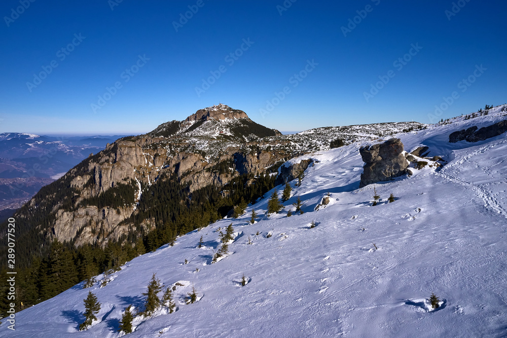 Aerial Landscape view from Ceahlău Mountains National Park and Toaca peak in the background in winter season