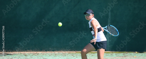 フォアハンドを打つ女子テニスプレイヤー