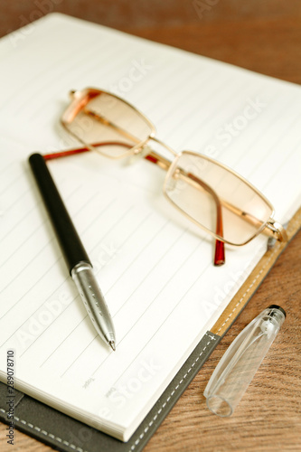 Workplace of writer with notebook and retro eyeglasses on wooden table 