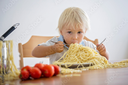 Little baby boy, toddler child, eating spaghetti for lunch and making a mess at home