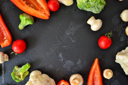 Fresh healthy vegetables. Vegetarian food. Sweet pepper, broccoli, cauliflower, mushrooms, tomato. Vegetables on a black dark background. Bright color food. Varied Food background. Place for text.
