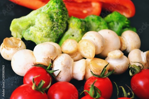 Fresh healthy vegetables. Vegetarian food. Sweet pepper  broccoli  cauliflower  mushrooms  tomato. Vegetables on a black dark background. Bright color food. Varied Food background. Place for text.