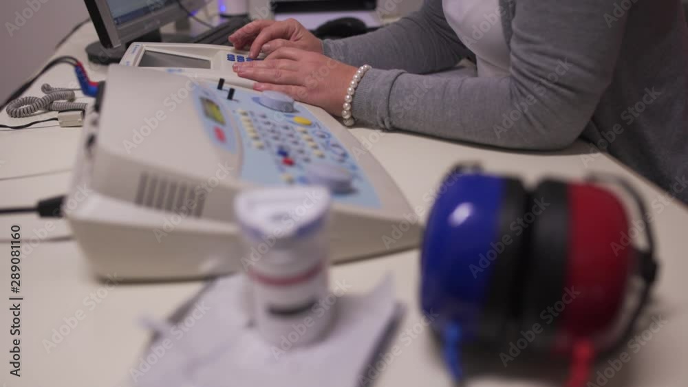 Doctor using machine medical device to for hearing test. Occupational health and safety for audio-metric testing. Doctor using machine medical device to for hearing test. Occupational health and safety for audio-metric testing.
