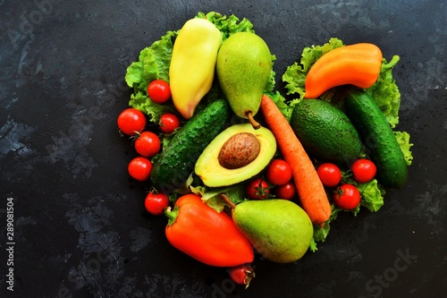 Composition with assorted fresh organic vegetables. Assorted fresh vegetables and fruits. Place for text. Cucumbers  tomatoes  pears  avocados  carrots  sweet peppers. Heart shaped vegetables.