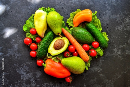 Composition with assorted fresh organic vegetables. Assorted fresh vegetables and fruits. Place for text. Cucumbers, tomatoes, pears, avocados, carrots, sweet peppers. Heart shaped vegetables.