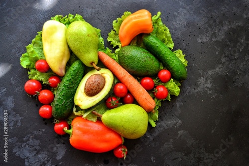 Composition with assorted fresh organic vegetables. Assorted fresh vegetables and fruits. Place for text. Cucumbers  tomatoes  pears  avocados  carrots  sweet peppers. Heart shaped vegetables.