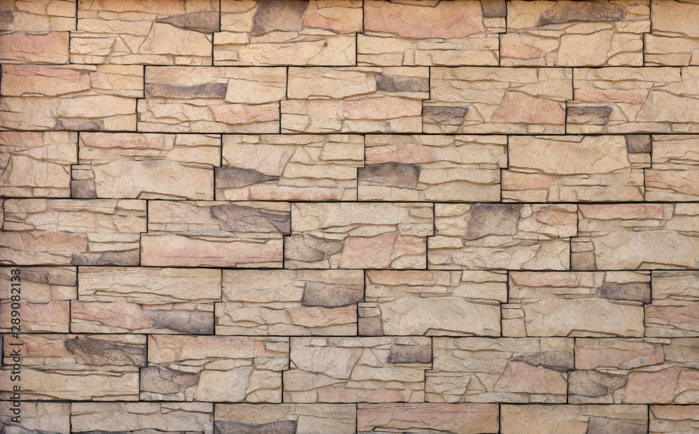 Fototapeta premium Textured beige wall made of artificial stone. Trendy modern abstract background.