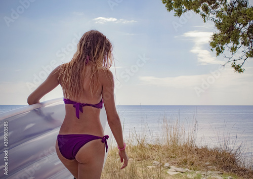 A slender girl in a purple swimsuit took an air mattress to swim in the sea.