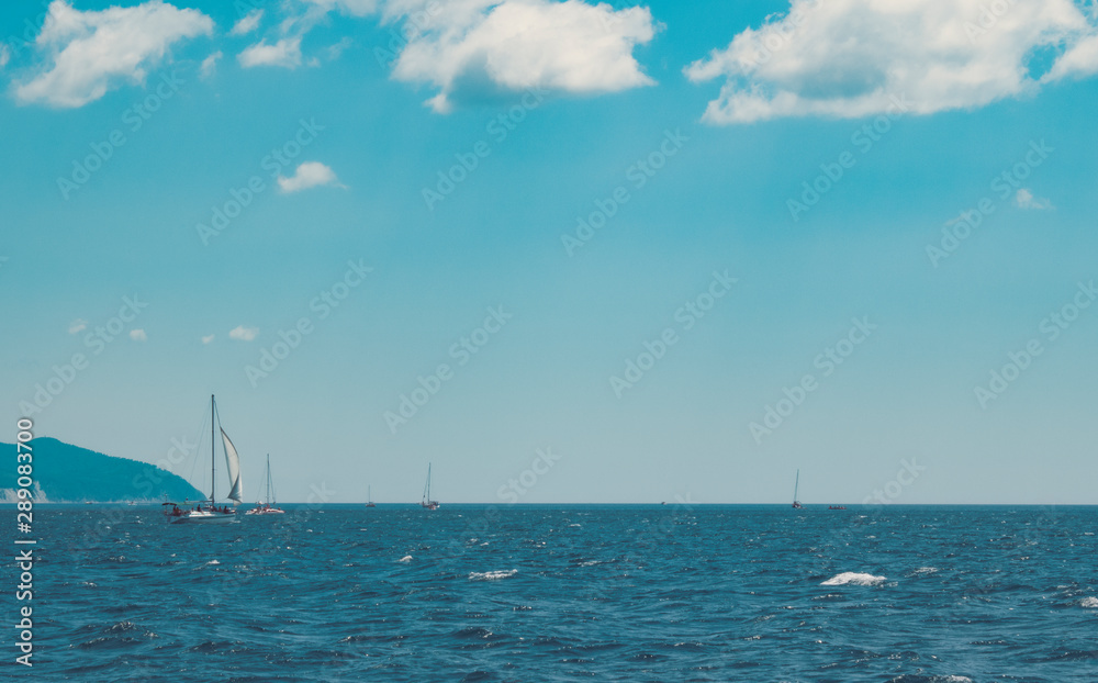 Yachts and small boats sail along the coast, hunt and fish. Boat trips on boats. Clear sky and sunny day Yachts and small boats sail along the coast, hunt and fish. Boat trips on boats. Clear sky and sunny day
