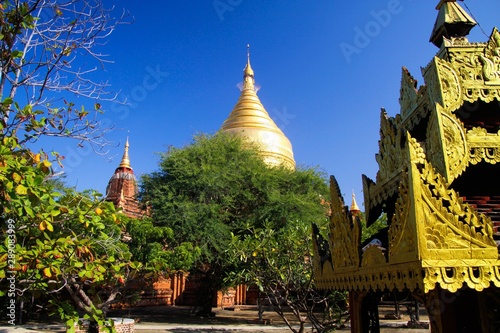 View on yard of buddhist temple with trees and golden pagoda - Bagan  Myanmar