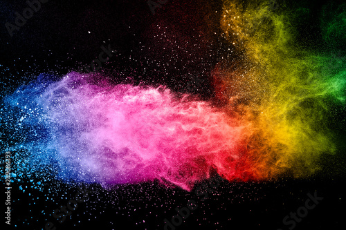 Abstract multicolored powder explosion on black background. Color dust particle splattered on background.