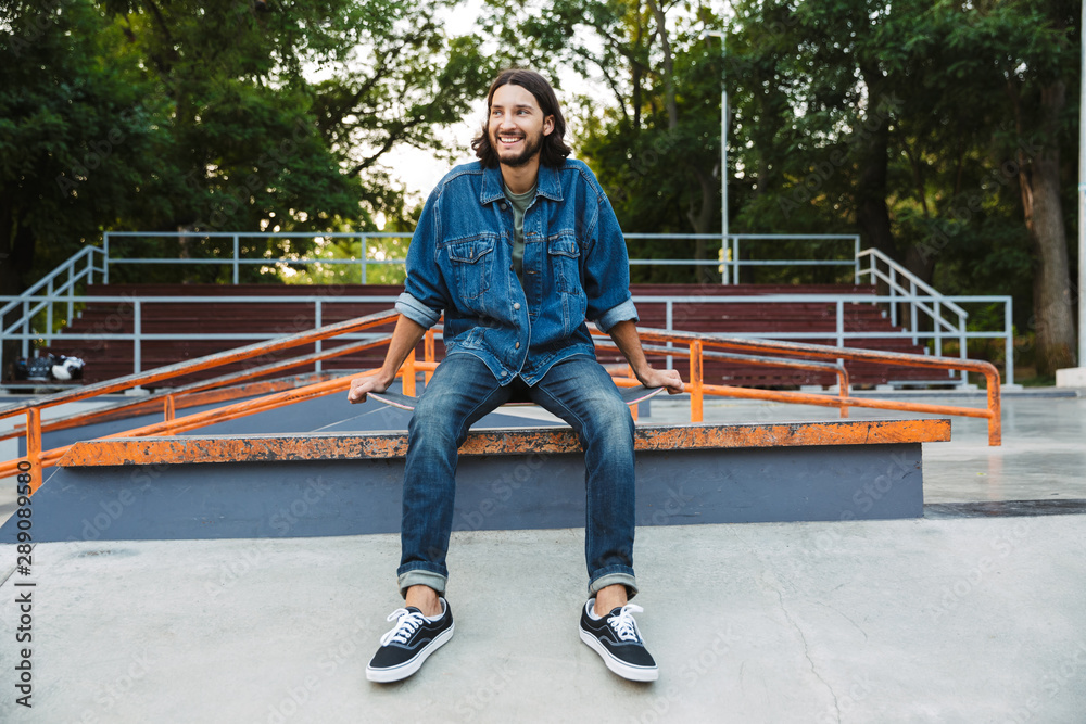 Attractive young hipster man sitting at the skate ramp Attractive young hipster man sitting at the skate ramp