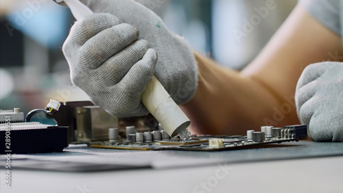 PC repair and maintenance in service center. Repairman puts thermal paste on processor of graphics chipset. Technician of computer technology at work.