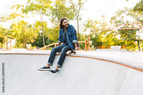 Attractive young hipster man sitting at the skate ramp