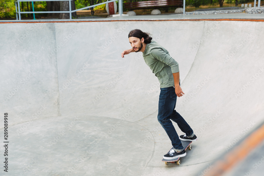 Handsome young hipster man skating on a skate ramp