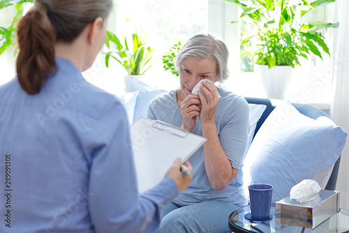 Psychotherapy session concept: elderly female client crying about painfull childhood memories with counselor.