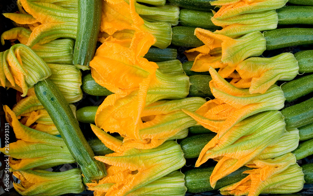 basket of small zucchini or courgette, green, full of edible flowers, yellow and orange, at local vegetable market, agriculture, food, farm, diet, vitamins, nutrition, summer, background, Milan, Italy