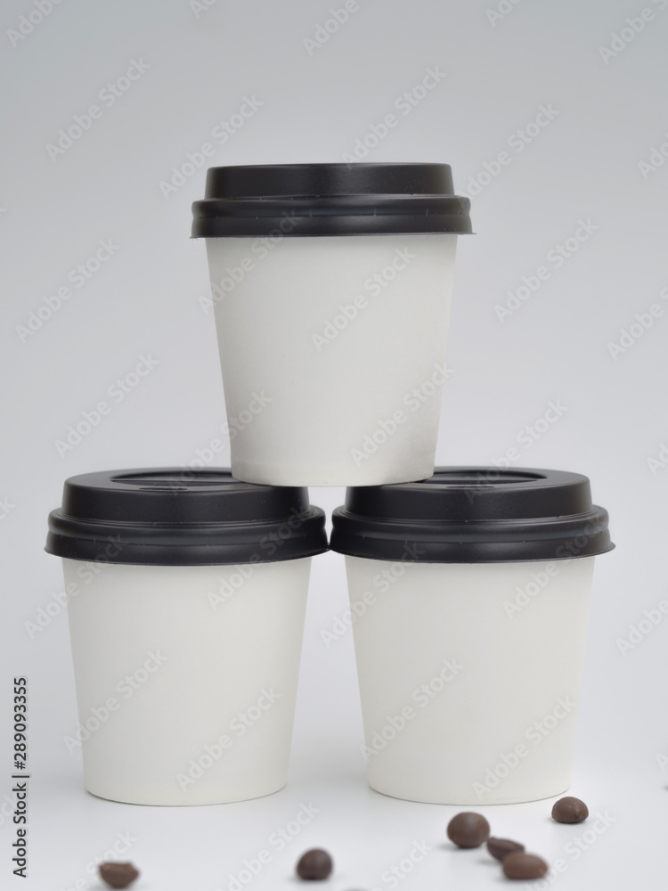 Pyramid made from white paper cups with coffee beans isolated on white. Mockup with copyspace Pyramid made from white paper cups with coffee beans isolated on white. Mockup with copyspace