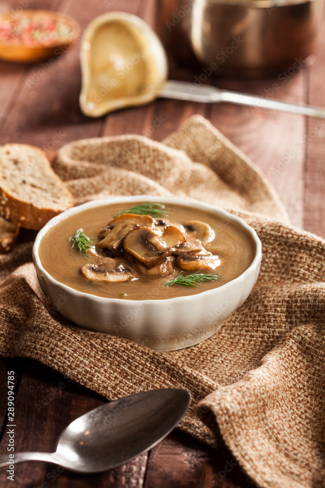 Delicious creamy mushroom soup with dill and close-up on a dark wooden background. Delicious creamy mushroom soup with dill and close-up on a dark wooden background.