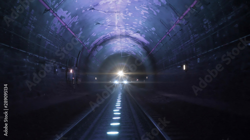 Bright train lights coming towards camera in a dark railway tunnel