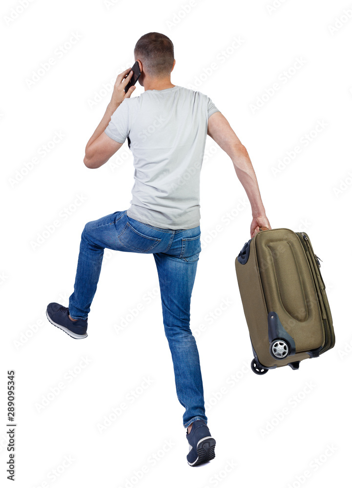 Back view of walking man with suitcase talking on the smartphone. Back view of walking man with suitcase talking on the smartphone.