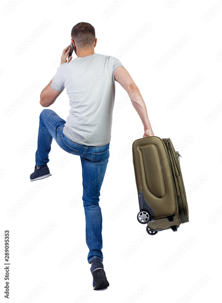 Back view of walking man with suitcase talking on the smartphone Back view of walking man with suitcase talking on the smartphone